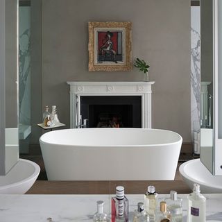 en suite bathroom with wash basin white bath tub and artwork