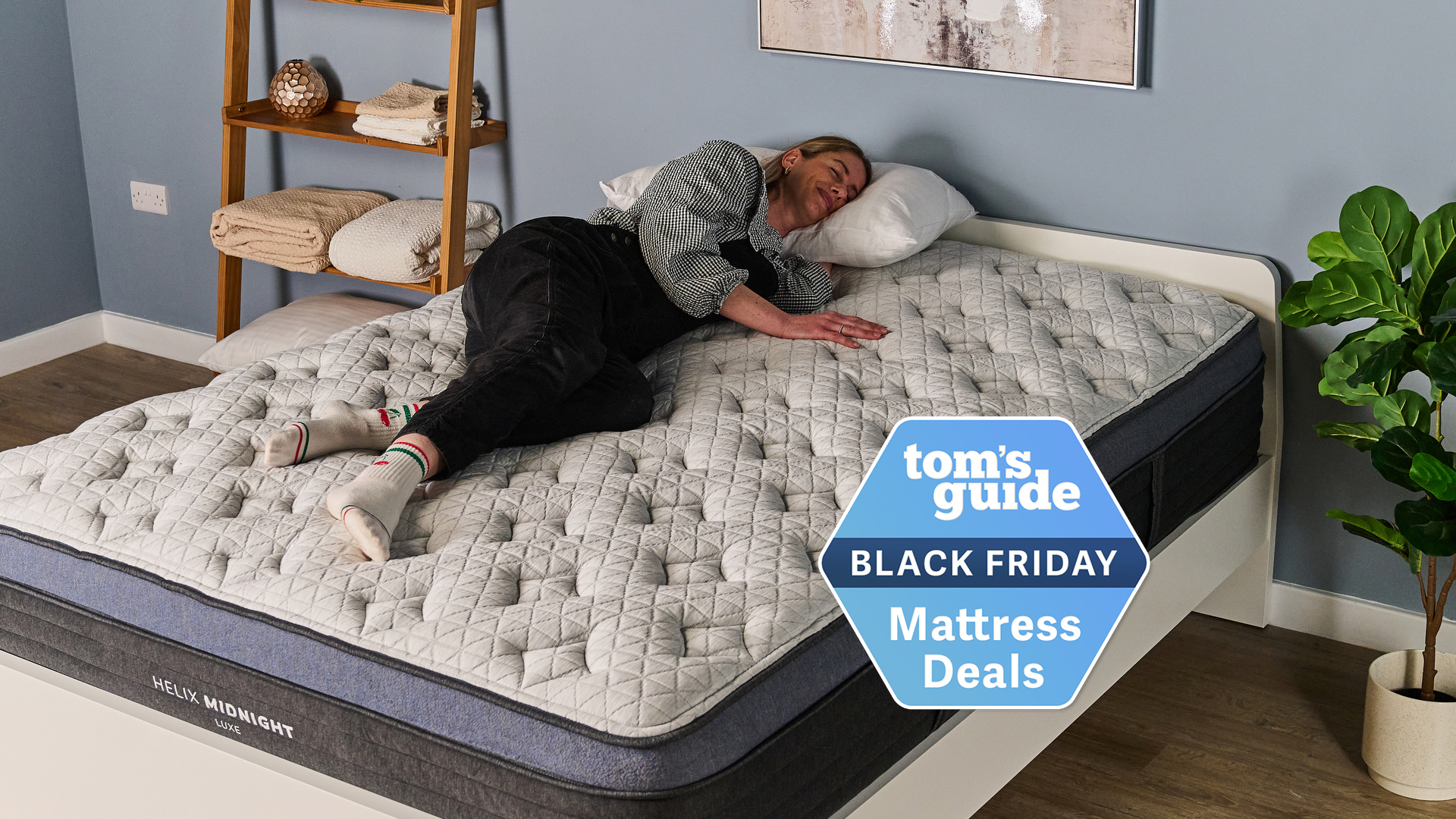 Sleep Editor Nicola Appleton sleeps on her side on the Helix Midnight Luxe mattress in our product testing lab, with a black Tom's Guide deals logo overlaid on the bottom right hand side