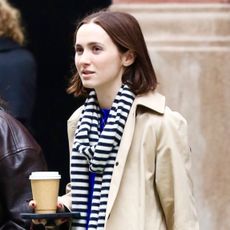 Maude Apatow wearing a trench coat and striped scarf