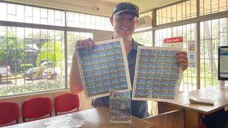 a man stands holding lots of stamps and smiles