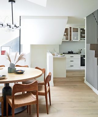 White kitchen with dining area with wooden table in Victorian mews house in London with contemporary interior designed by Kitesgrove