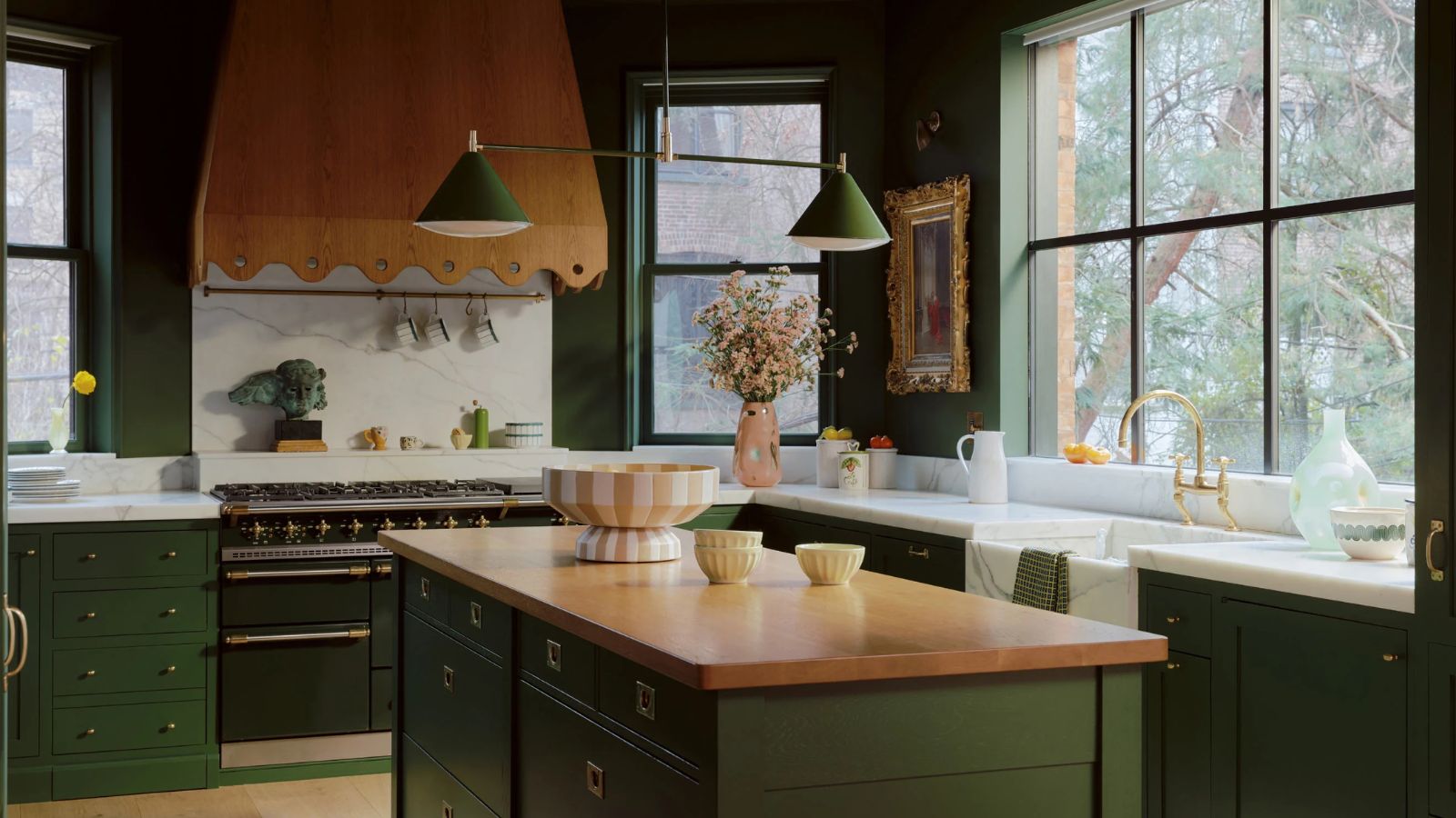 dark green kitchen with wooden countertop and wooden scalloped range cooker hood with large windows and green pendant light