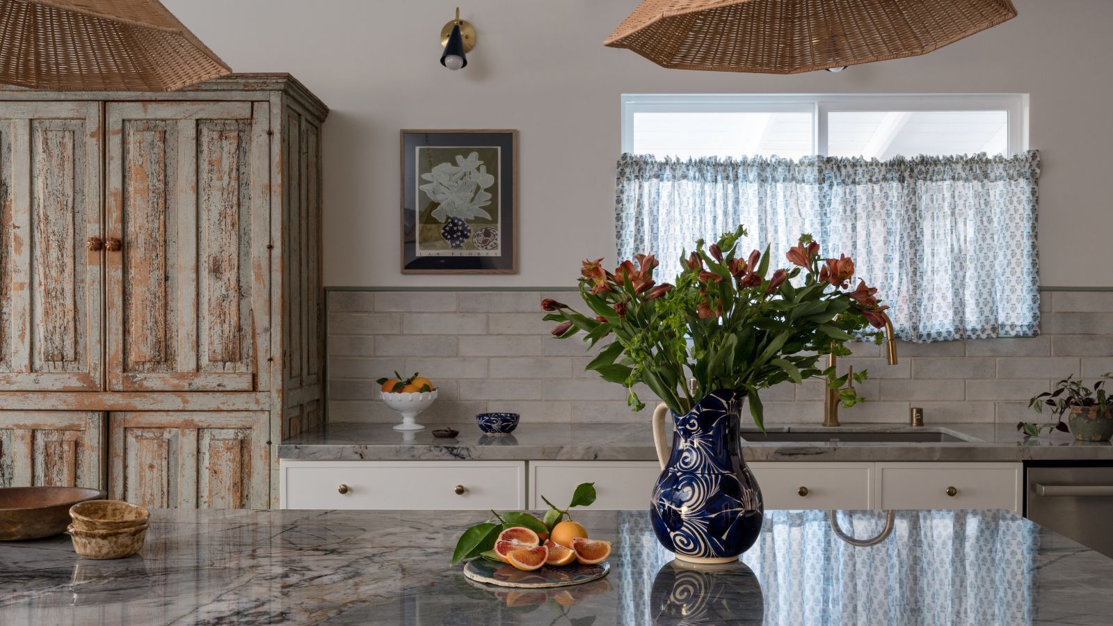 rustic vintage inspired kitchen design my Gilded Hearth with a blue marble countertop and a window dressed with a blue floral cafe curtain