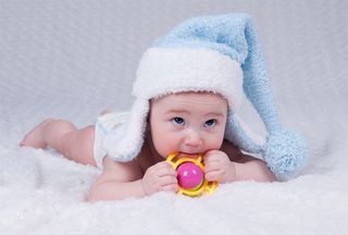 a cute newborn baby with a pale-blue winter hat on.