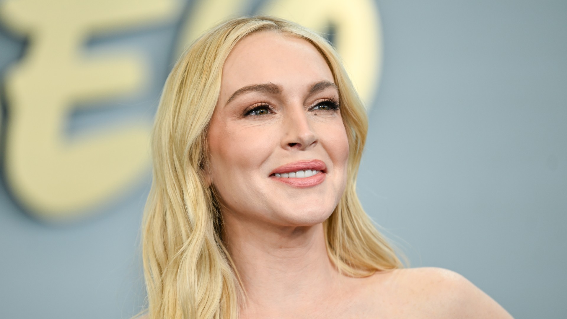 lindsay lohan poses on a red carpet at a disney event