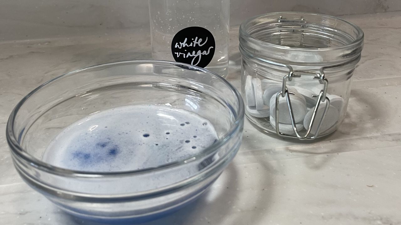 Jar of denture tablets next to bottle of white vinegar and bowl filled with jewellery