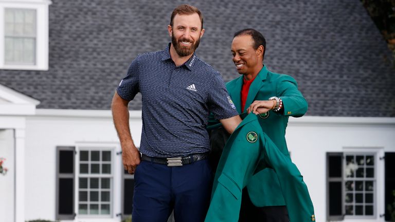 Dustin Johnson receives the Green Jacket from Tiger Woods