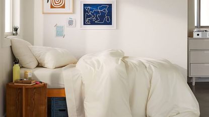 A cooling comforter on a bed against a white wall with wall art.