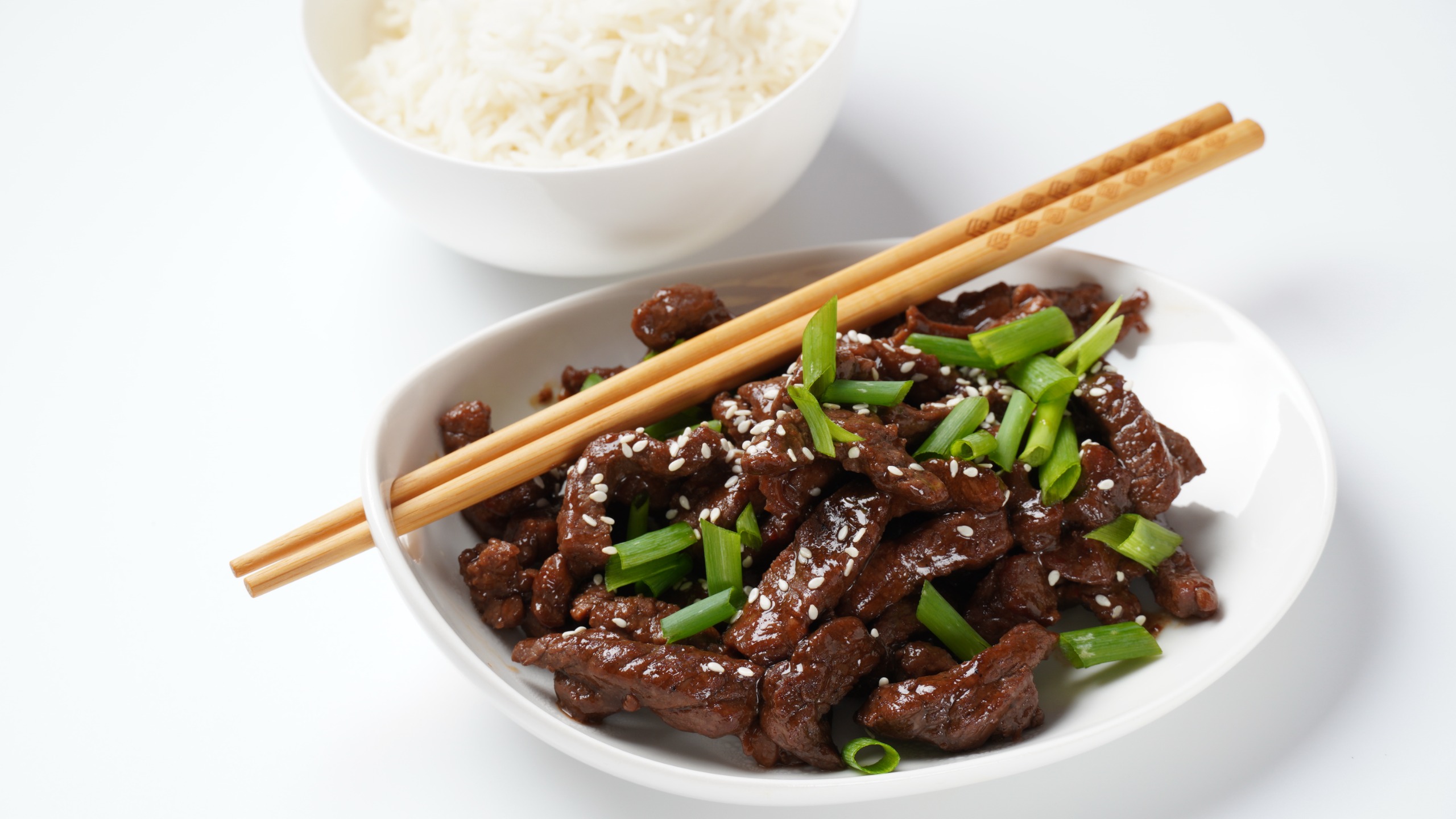 A bowl of Mongolian beef with chopsticks
