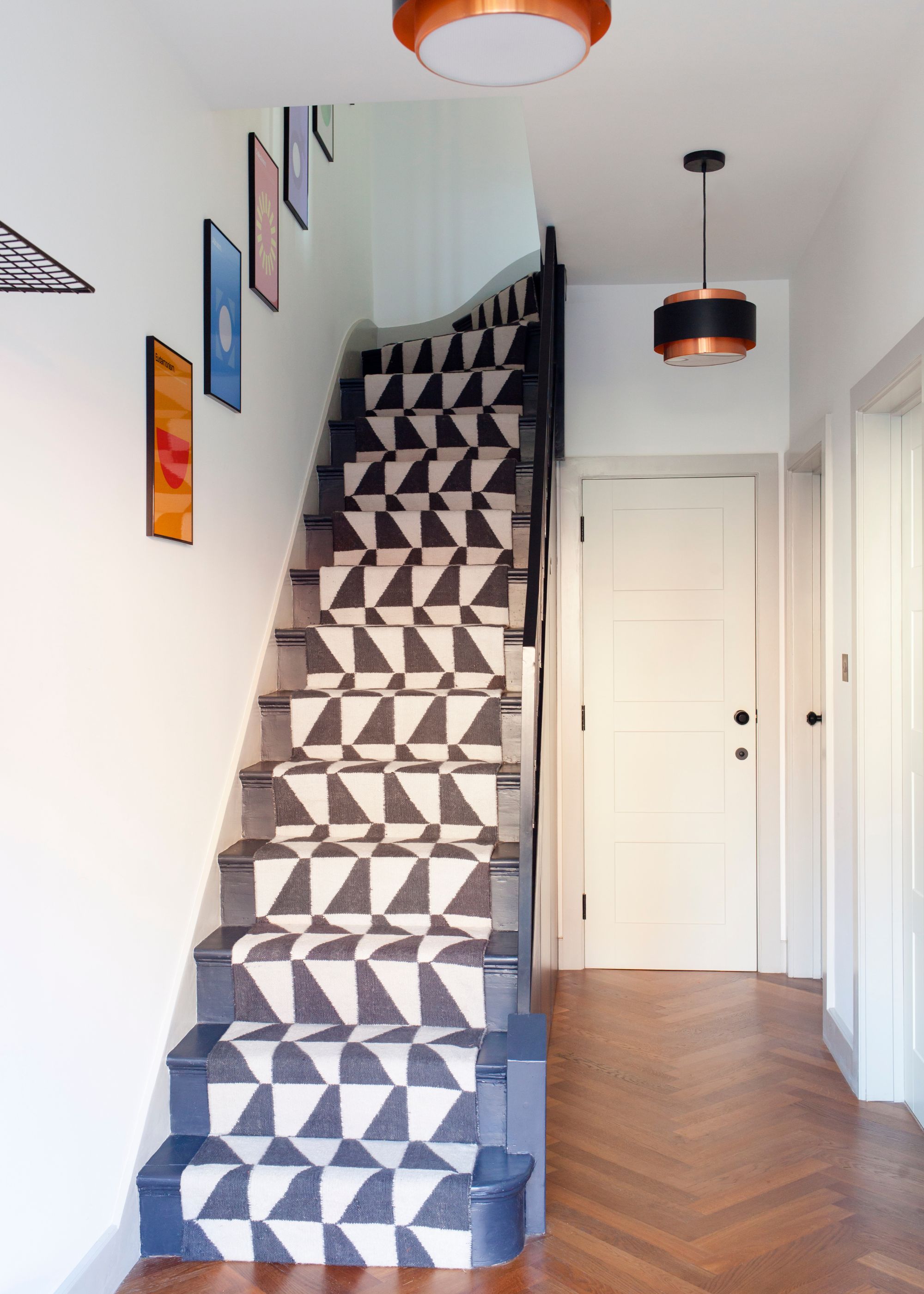 hallway with parquet floors, white walls and geometric print stair runner