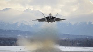 A U.S. fighter jet takes off from a runway in Alaska and flies toward snowy mountains
