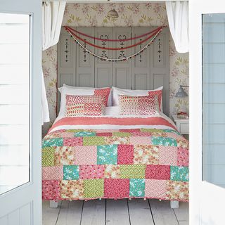 light and airy bedroom with veranda patchwork bed linen and floral wallpaper