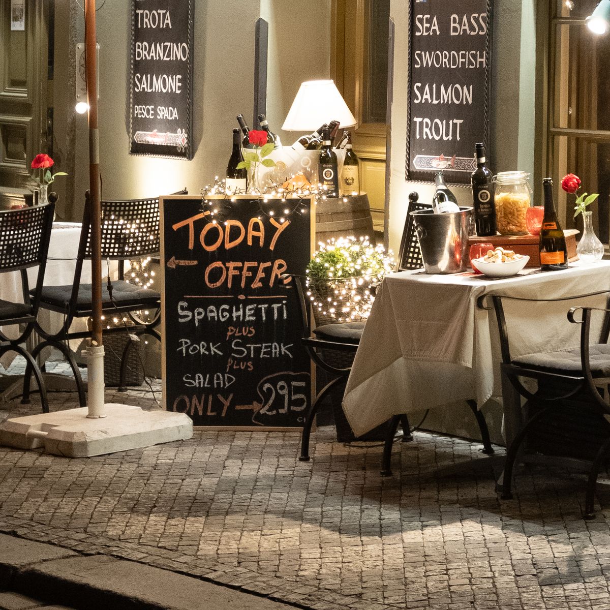 A restaurant in Prague on a cobbled street lit up at night