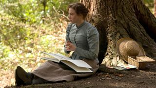 En bild från påskfilmen Miss Potter, där huvudrollen sitter och tecknar under ett träd en solig dag.