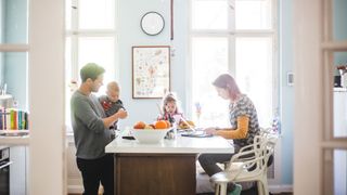 Ways to save space in your kitchen: Image shows family at kitchen breakfast bar