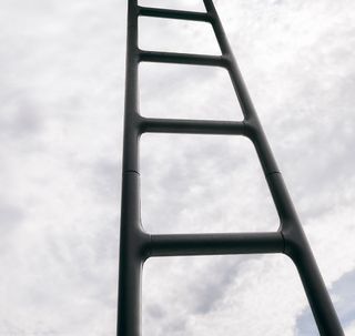 A black ladder with the sky in the background