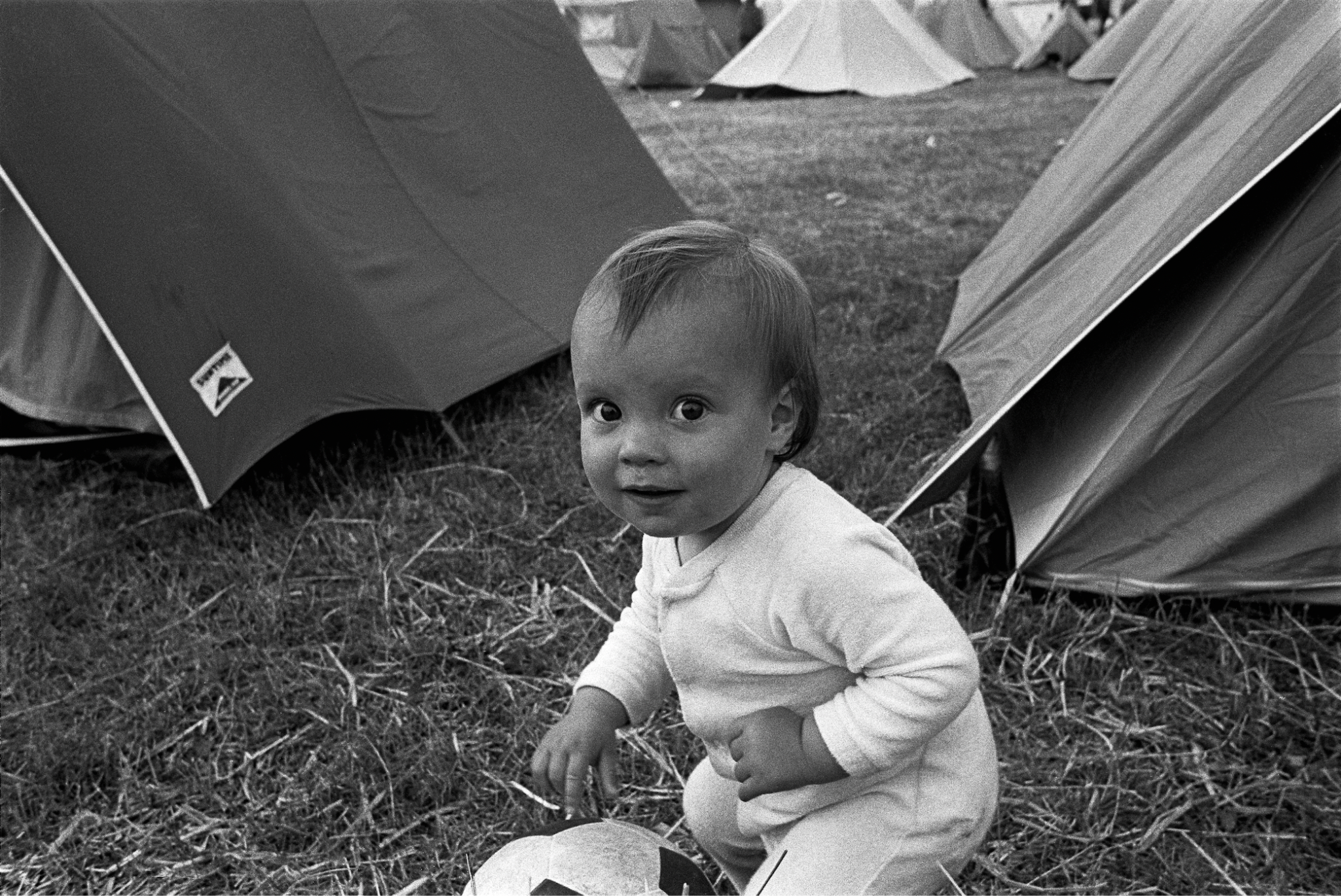 A baby Lily Allen in front of some tents at Glastonbury in the 1980s