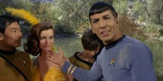 Leonard Nimoy's Spock smiling next to a woman in feathers and Sulu in Shore Leave episode of Star Trek