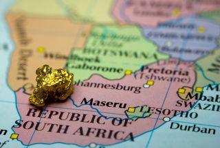Close-up of a gold nugget on top of an old map of South Africa