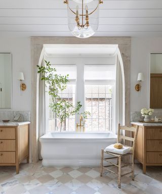 neutral bathroom with checkerboard tile floor white bath tub and two wooden vanities