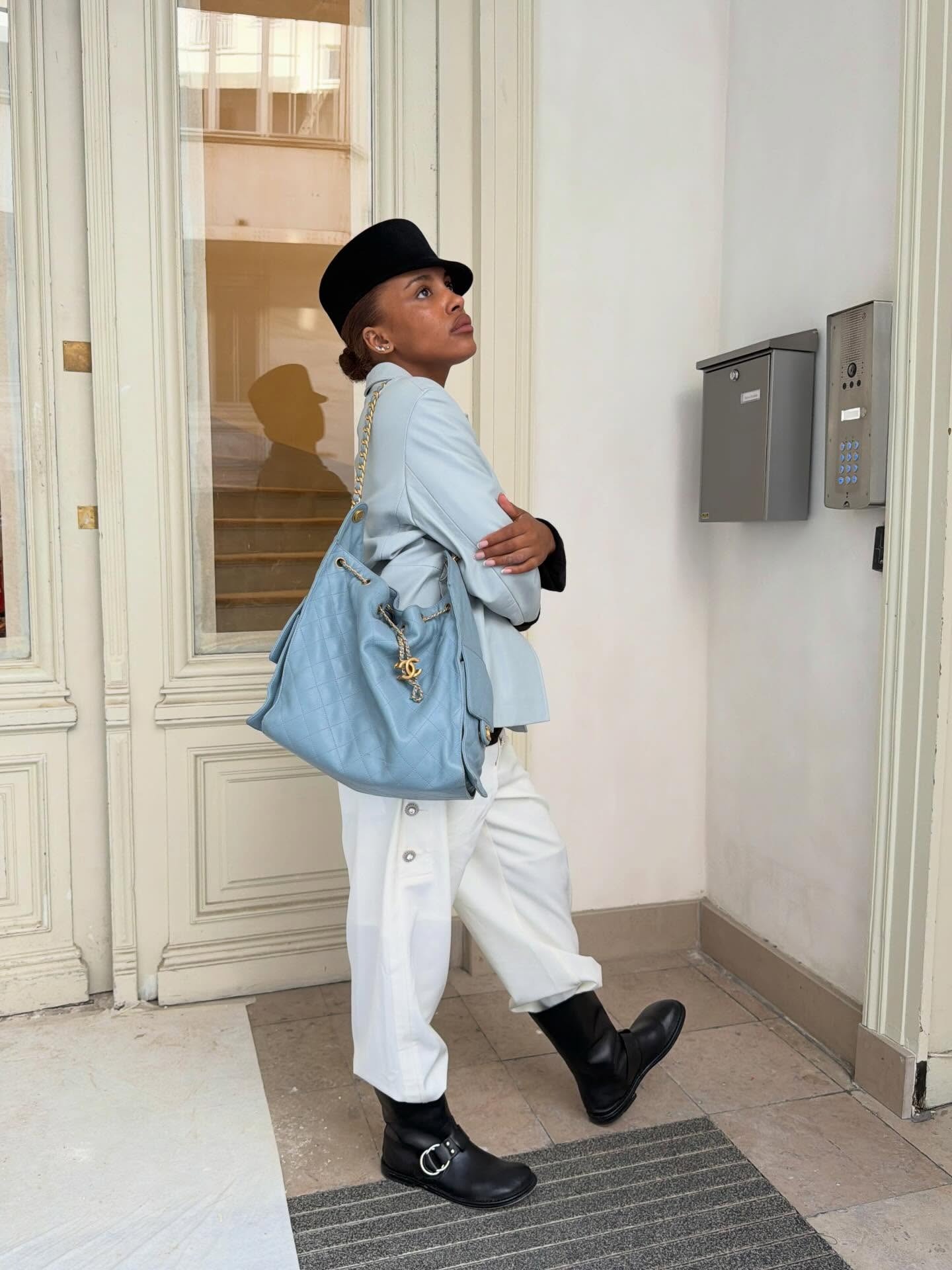 @mv.tiangue wearing a Chanel bag, white pants, icy blue coat, and half-boots