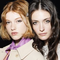 two models with blurred skin and wavy hair backstage at fashion week