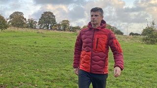 Hiker wearing a Peak Performance Helium Utility Flo Jacket on hillside