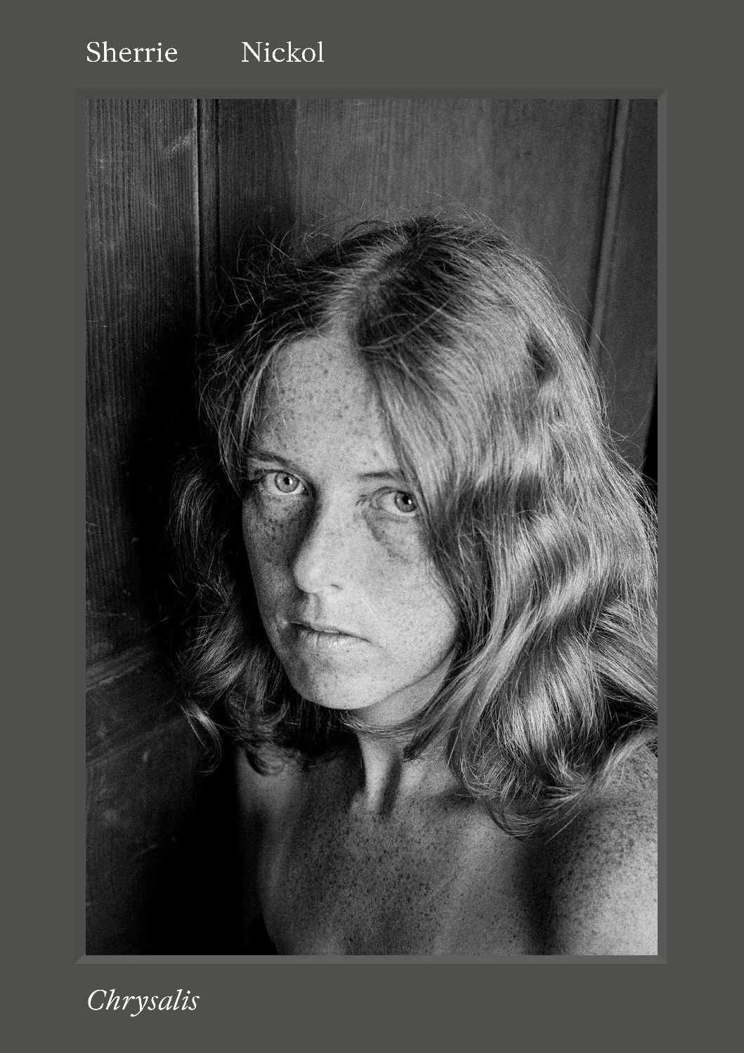 The front cover of the book Chrysalis by Sherrie Nickol, featuring a black-and-white close-up portrait of a freckled woman with wavy hair looking directly at the camera.