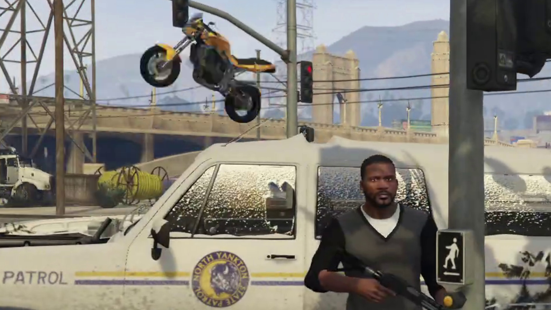 Franklin poses in front of a snow-covered cop truck as a motorbike flies through the air behind him.