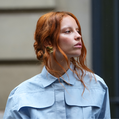 Face the Future A guest wears a full Patou outfit with a light blue button-up shirt with a structured collar and oversized chest pockets. Hair is styled in loose waves, and earrings are visible, outside Patou, on June 06, 2025 in Paris, France 