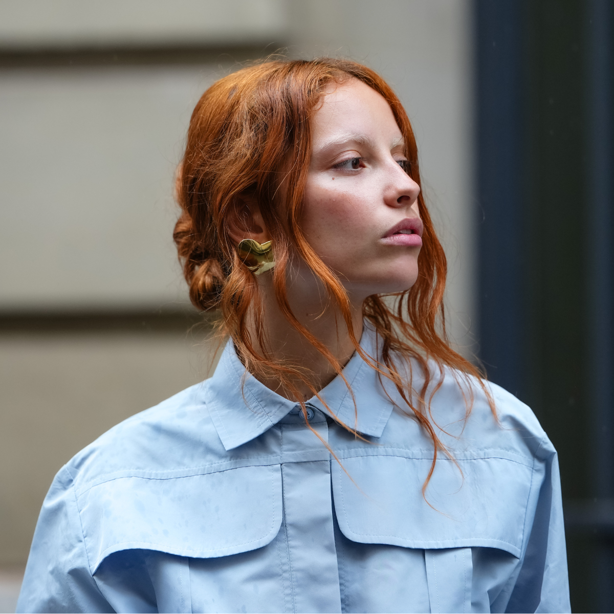 Face the Future A guest wears a full Patou outfit with a light blue button-up shirt with a structured collar and oversized chest pockets. Hair is styled in loose waves, and earrings are visible, outside Patou, on June 06, 2025 in Paris, France 