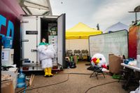 Photo titled Headless Chicken by Marc James: a performer at the World Halal Food Festival escapes the heat of their chicken costume by cooling off in a refrigeration truck, costume head on a chair.