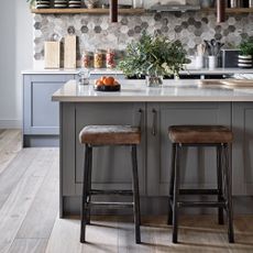 kitchen with grey hexagon designed wall grey cabinets wooden stool and white counter