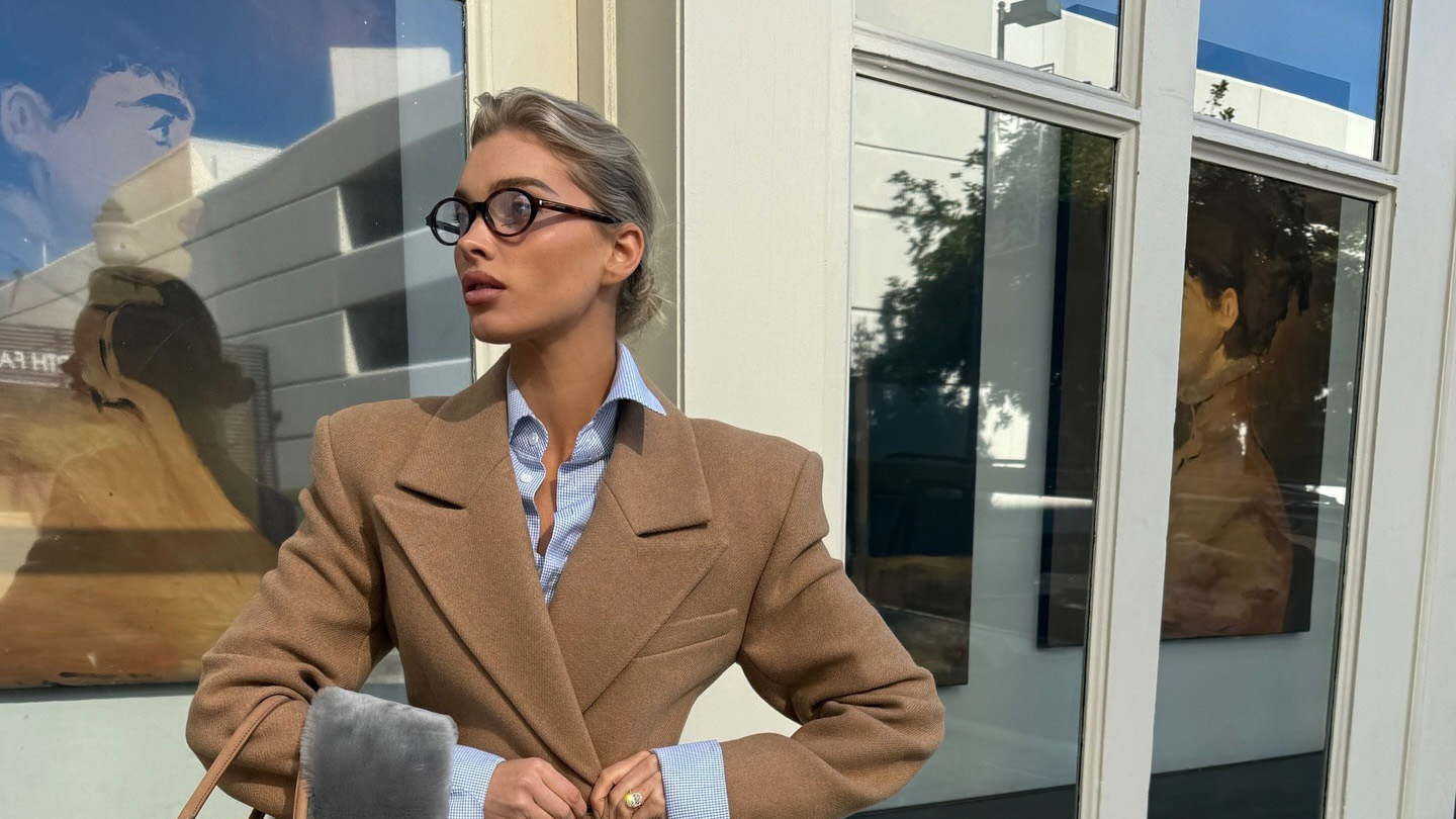 Elsa Hosk wearing a camel blazer and suede pencil skirt with pumps, a blue shirt, and a gray fur scarf