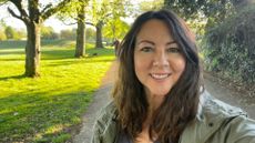 Susan Griffin doing 10-minute walking workout through sunny park, smiling