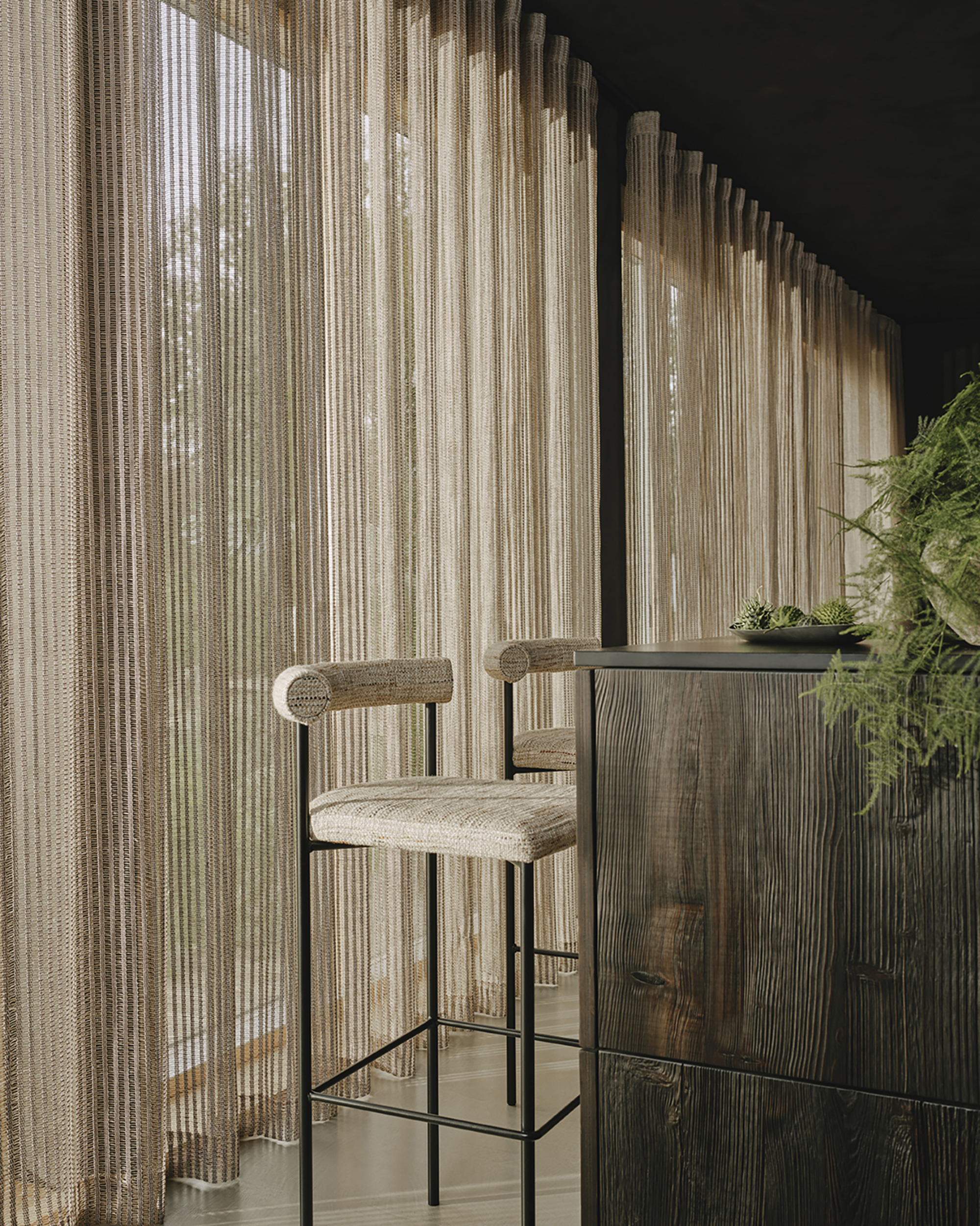 kitchen island bench with tall bar stools with wall of sheer curtains in beige color