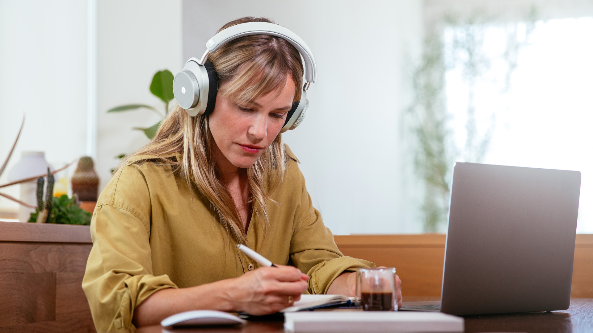 Woman wearing Neurable's headphones, at a desktop computer