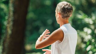 Rear view of woman doing tai chi in garden at home