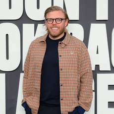 Rob Beckett in beige check shirt and black t-shirt at Oasis Don't Look Back In Anger premier.