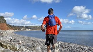 Runner on beach wearing the Nathan TrailMix 2.0 12L Hydration Pack