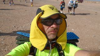 Mature trail runner Robert Duncombe with yellow cap, sunglasses and sun shield on sand