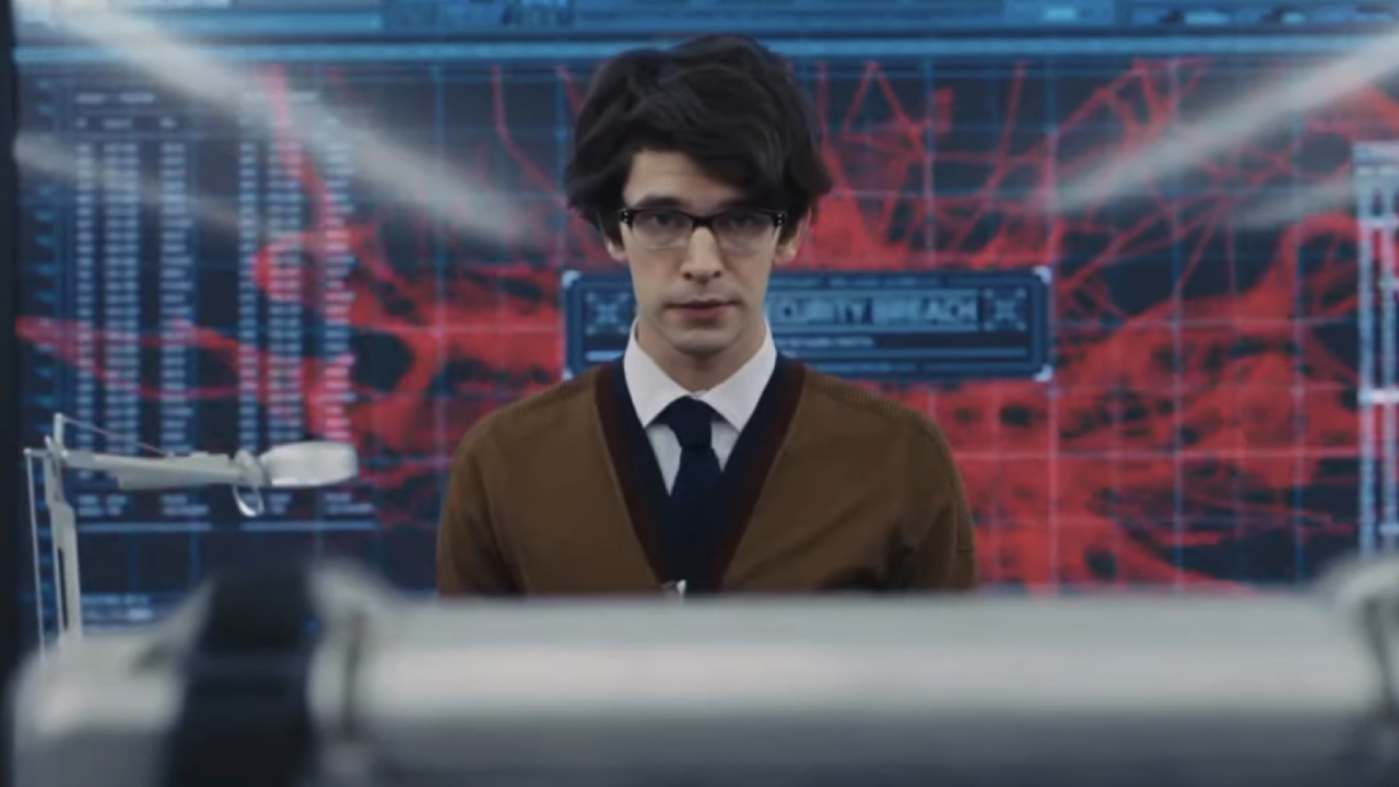 Ben Whishaw as Q standing in front of a large computer screen in Skyfall