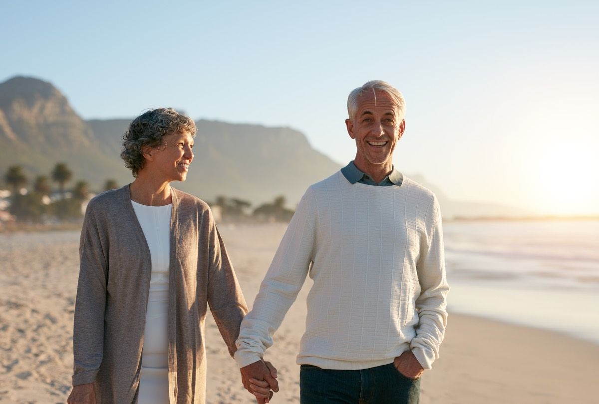 An older couple taking a walk on the beach.