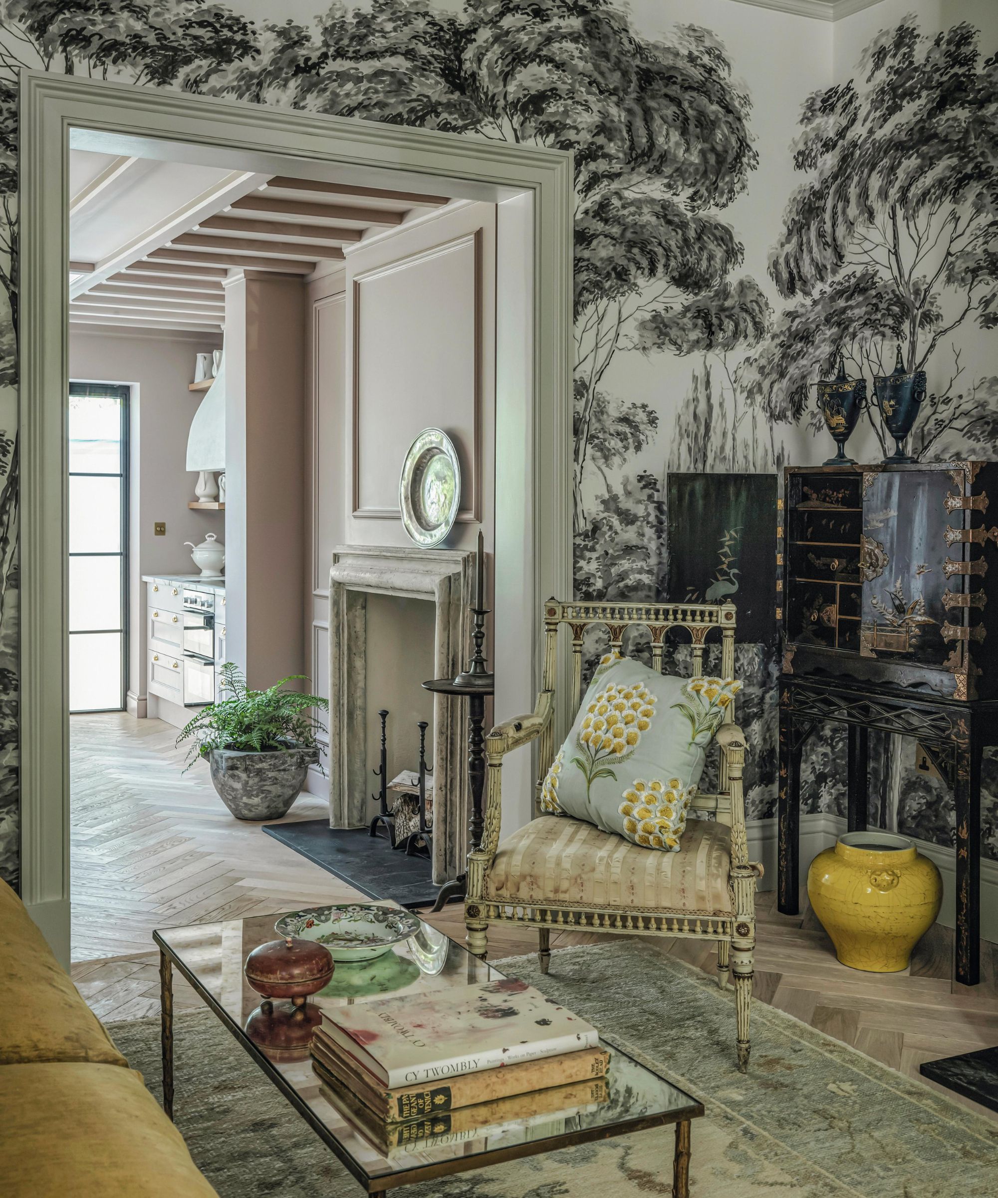 a lavish large london sitting room with mural wallpaper and a chinoiserie style cabinet, antique arm chair and yellow sofa