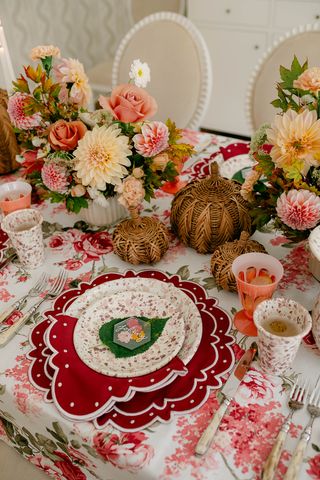 a fall tablescape with arcylic pressed flower place card, woven pumpkins and red napkins