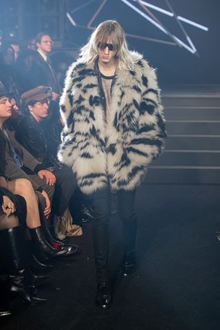 Man on Celine runway in furry animal print coat and dark glasses