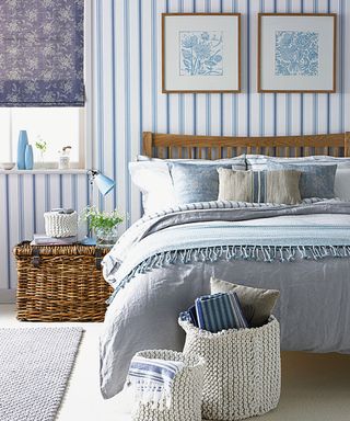 bedroom with blue striped wallpaper and bed with blue designed cushion