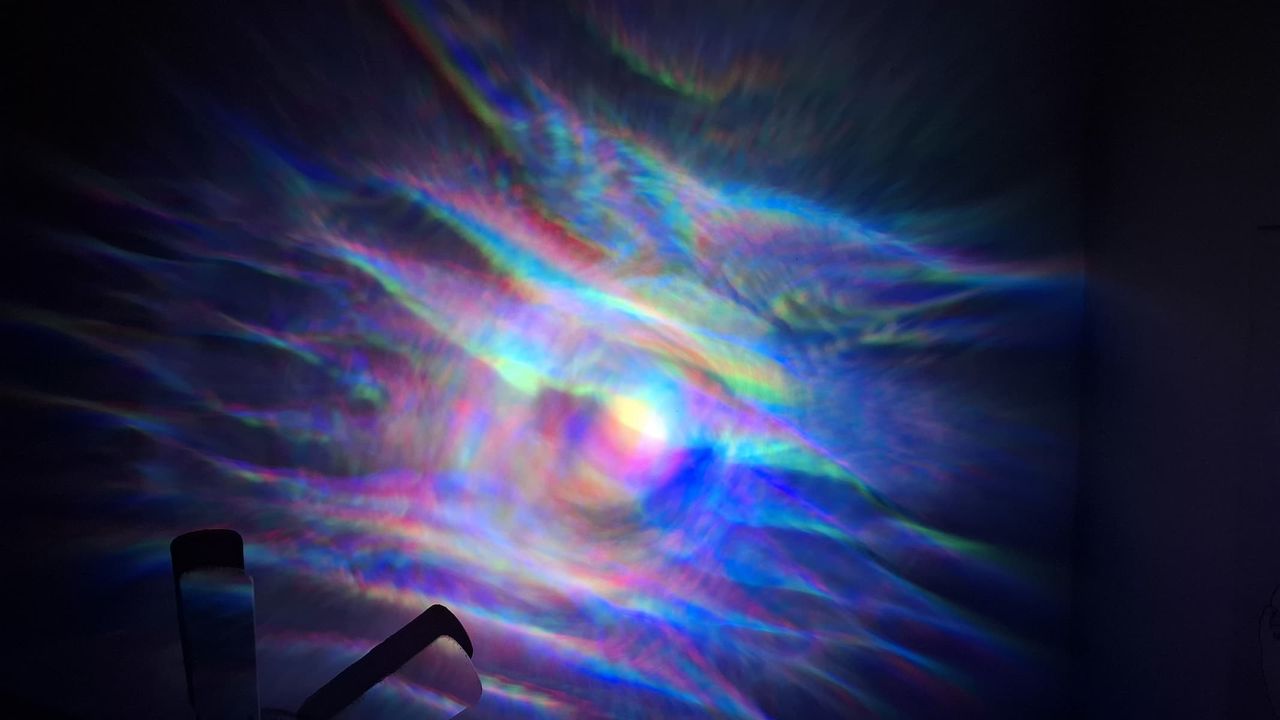 A multicolor projection is on a wall in a dark room.