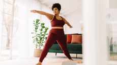 Woman practices Pilates standing on a mat in her home