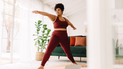 Woman practices Pilates standing on a mat in her home